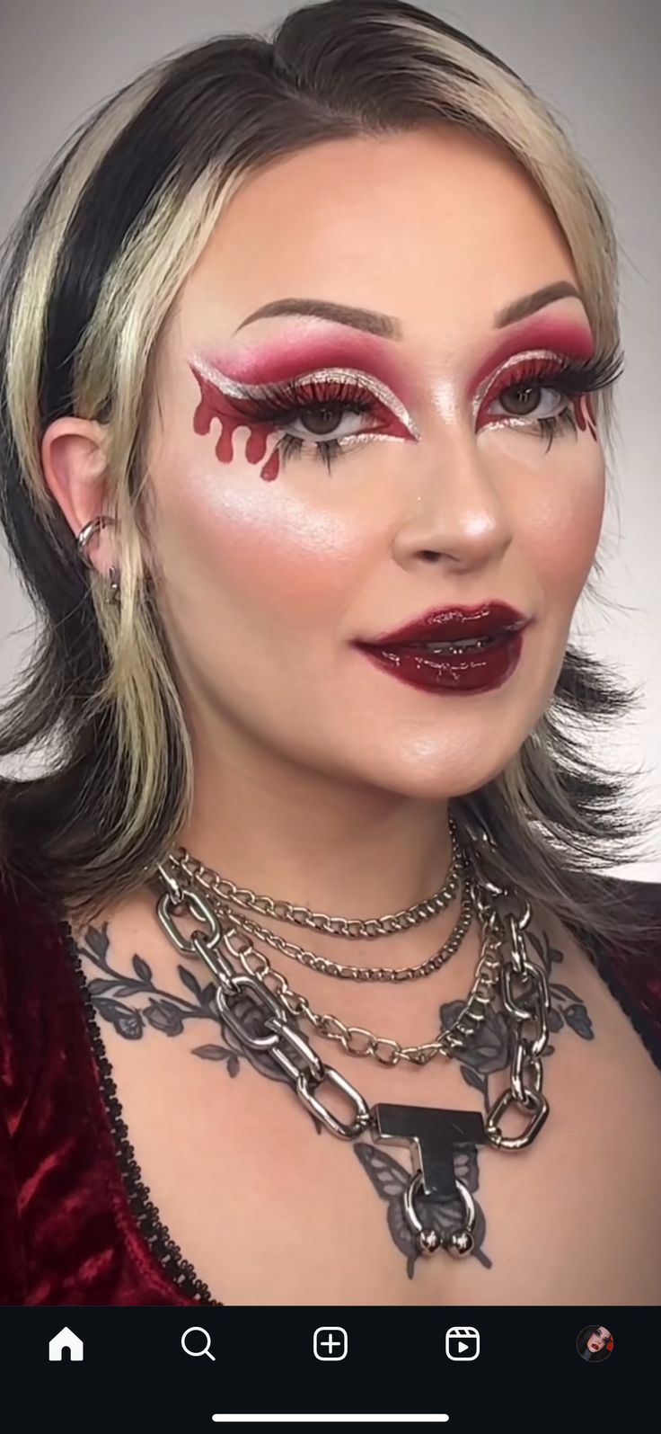 a woman with red makeup and chains on her neck is looking at the camera while she's taking a selfie