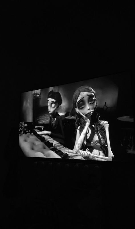 a black and white photo of two people on a television screen in the dark,