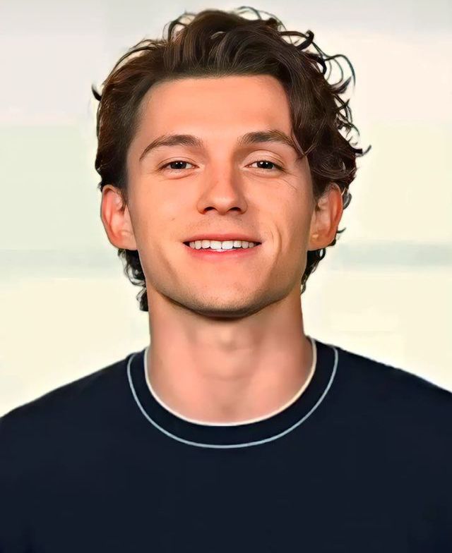 a man with curly hair smiling at the camera and wearing a black t - shirt