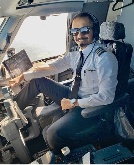 a man sitting in the cockpit of an airplane wearing headphones and holding a laptop