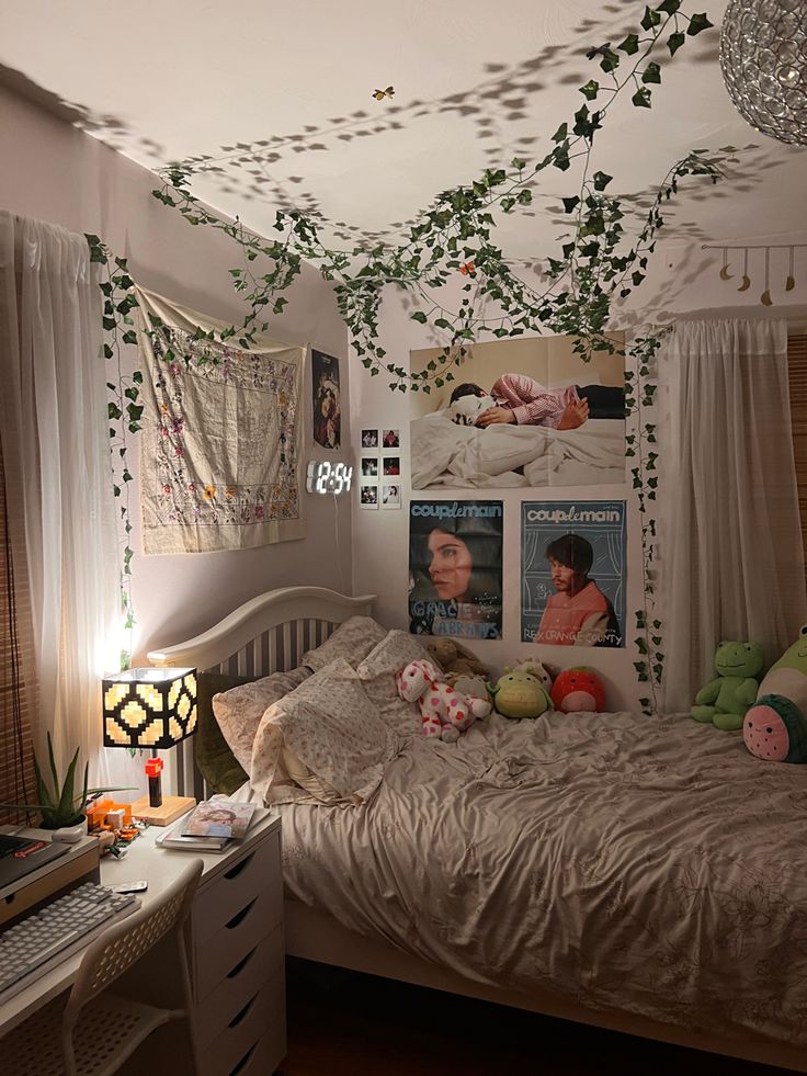 an unmade bed in a bedroom with pictures on the wall and plants hanging from the ceiling