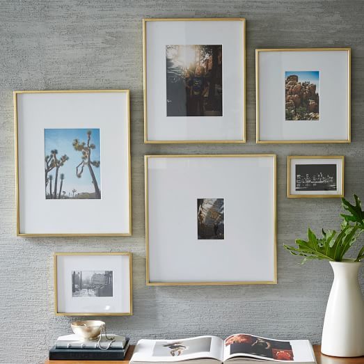 a table with some pictures on the wall and a potted plant in front of it