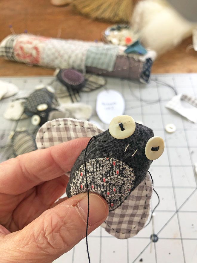 someone is stitching together some fabric with buttons on it and sewing needles in front of them