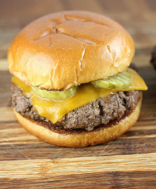 a hamburger with cheese and pickles on it