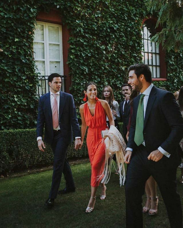 a group of people walking across a lush green field next to a building with ivy covered walls