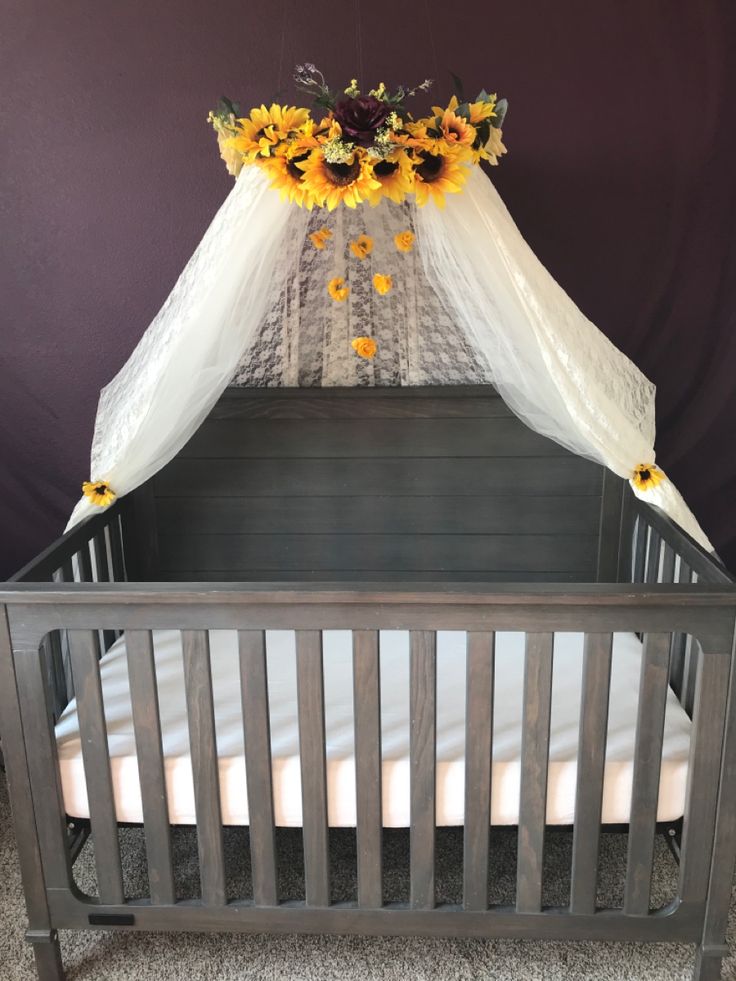 a baby crib with sunflowers on top and white netting over the bed