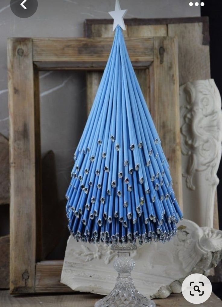 a small blue christmas tree made out of paper straws on top of a table