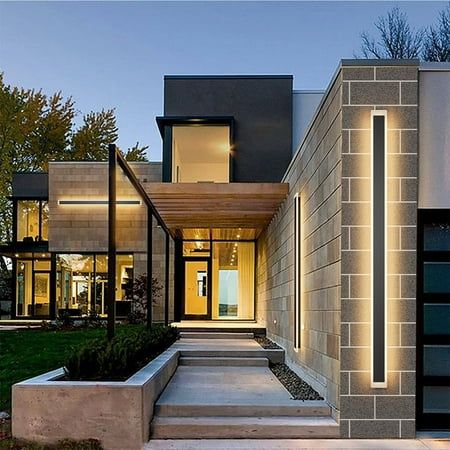 a modern house with stairs leading to the front door and side entrance at night time