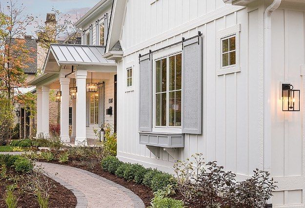 a white house with grey shutters on the front door and side walk leading up to it