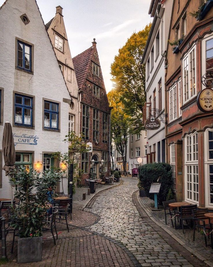 a cobblestone street with tables and chairs on both sides in an old european town