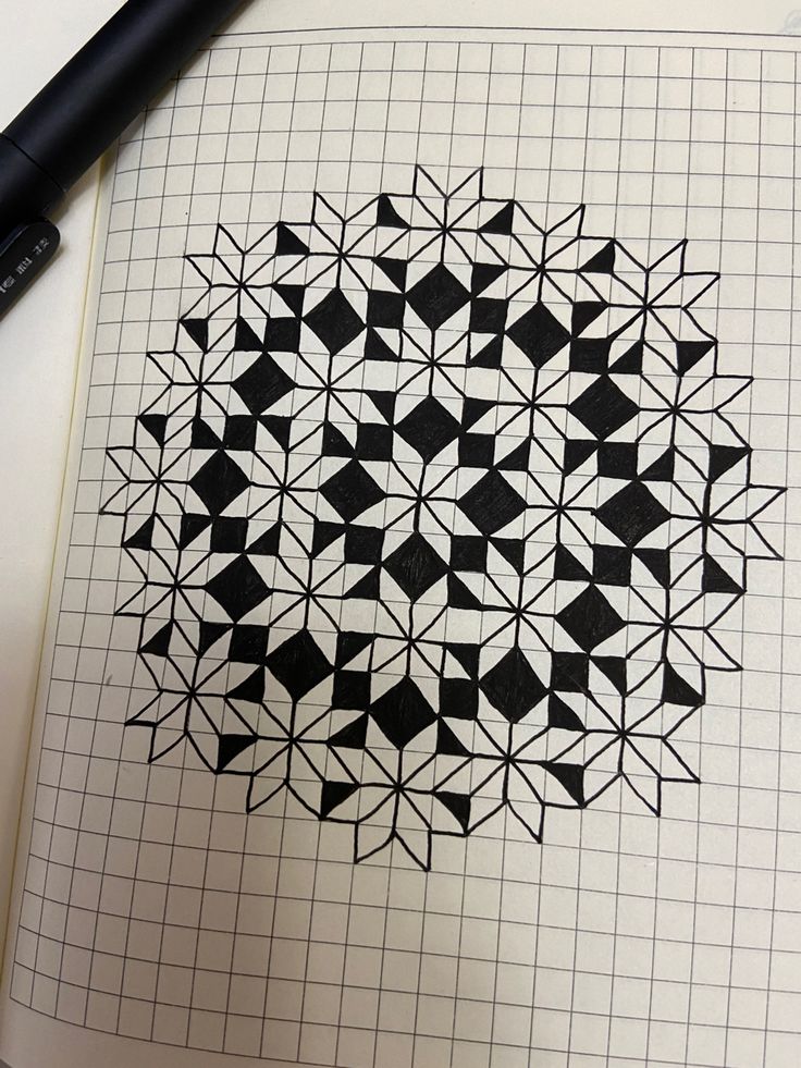 a black and white drawing on top of a notebook with a pen next to it