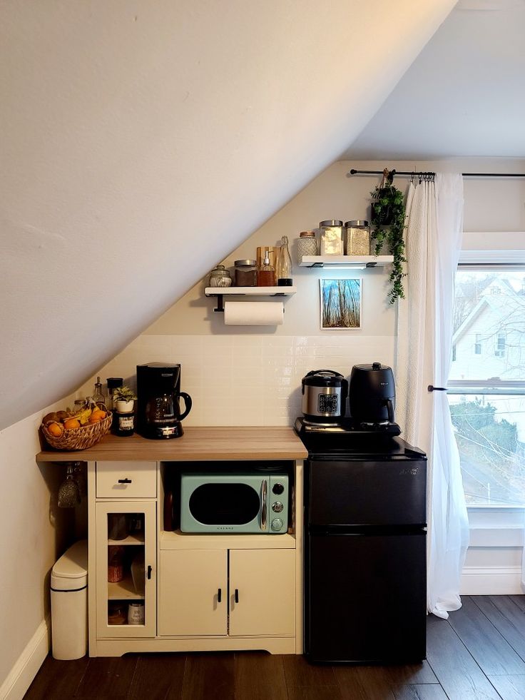 a small kitchen with an oven, microwave and coffee pot on the counter in front of a window