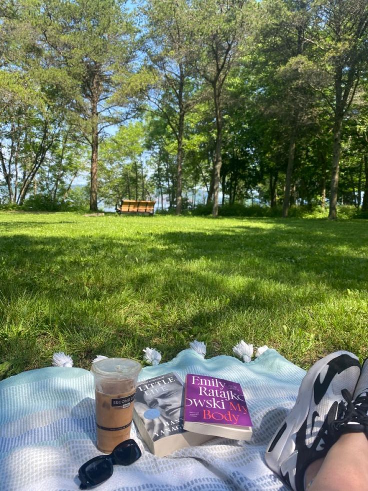 a person laying on top of a blanket next to a cup of coffee and book