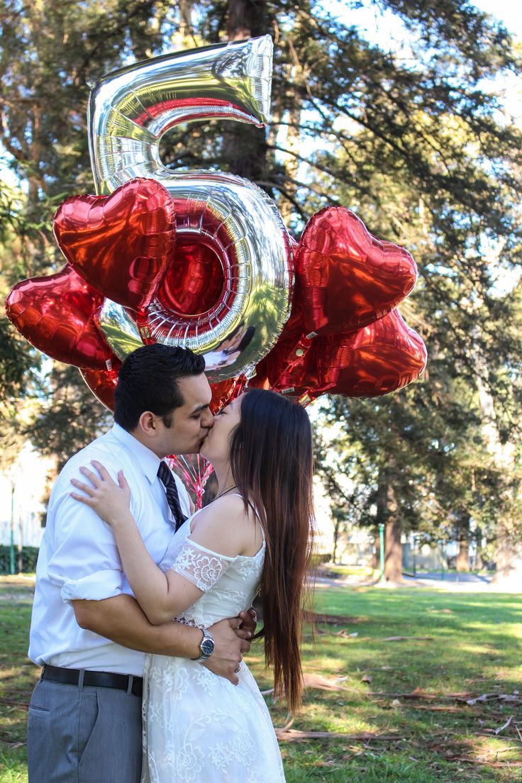 a couple kissing in front of the number five balloon