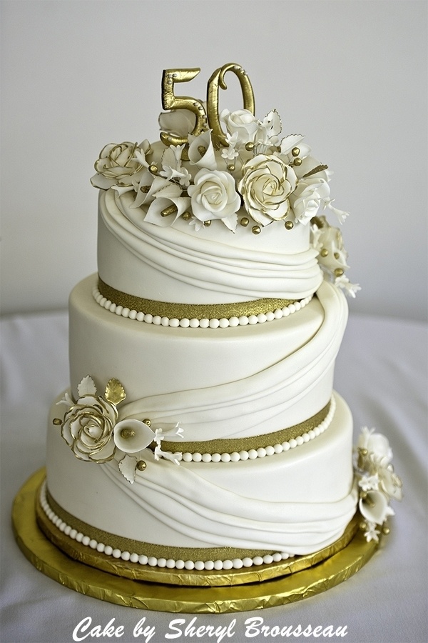 a white wedding cake with flowers and the number 50 on it's top tier