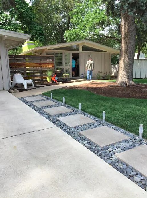 a man standing in the back yard of a house next to a tree and grass