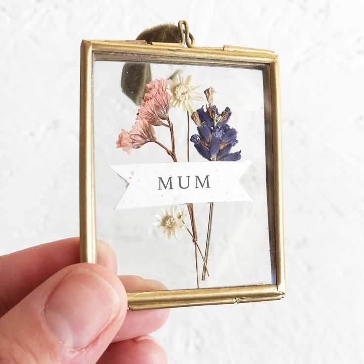 a person holding up a small glass frame with flowers on it that says a & f