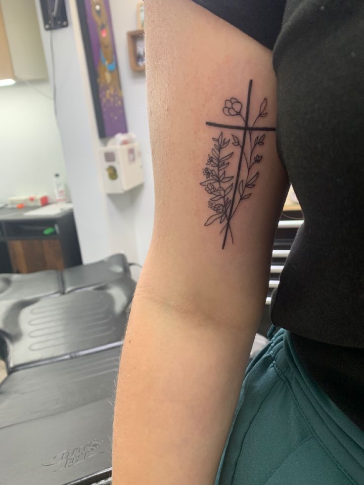 a woman with a cross and flowers tattoo on her arm