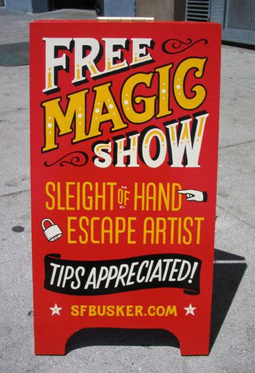 a free magic show sign on the sidewalk