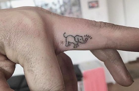 a small elephant tattoo on the left side of the finger is shown in black ink