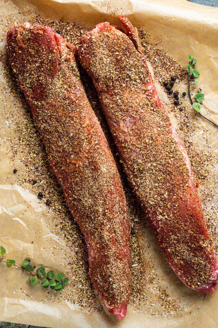 pork tenderloin with spices and seasoning on top, sitting on parchment paper