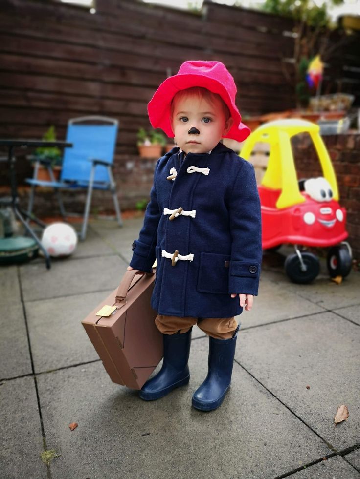 a small child wearing a red hat and blue coat with a suitcase in his hand