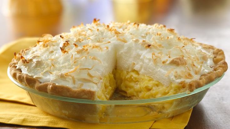 a pie sitting on top of a yellow napkin next to a glass bowl filled with food