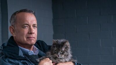 a man holding a cat in his arms while wearing a blue jacket and looking at the camera