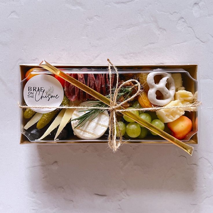 a box filled with assorted fruits and cheeses on top of a white table