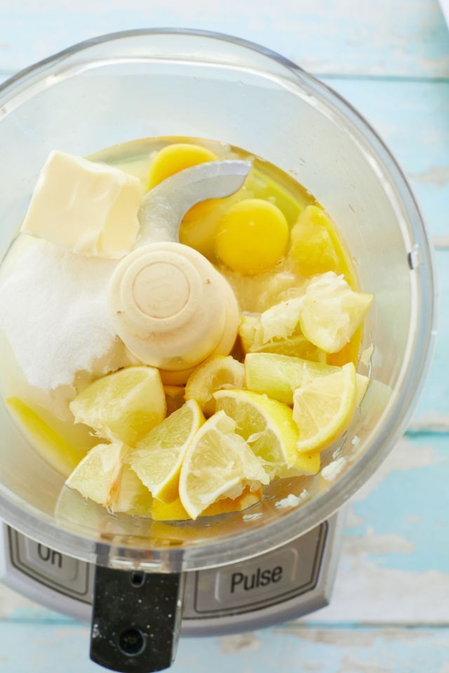 a food processor filled with fruit and ice cream on top of a blue wooden table