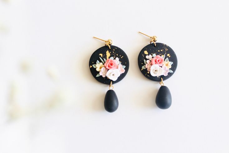 the earrings are decorated with flowers and black stone tears, along with gold - plated hooks