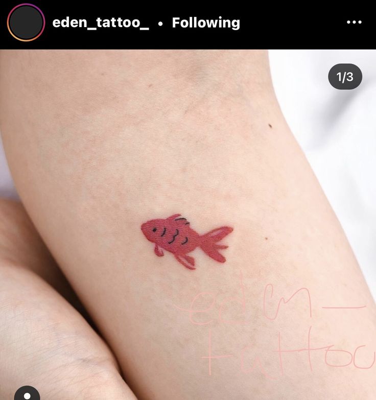 a small tattoo on the back of a woman's leg with a goldfish in it