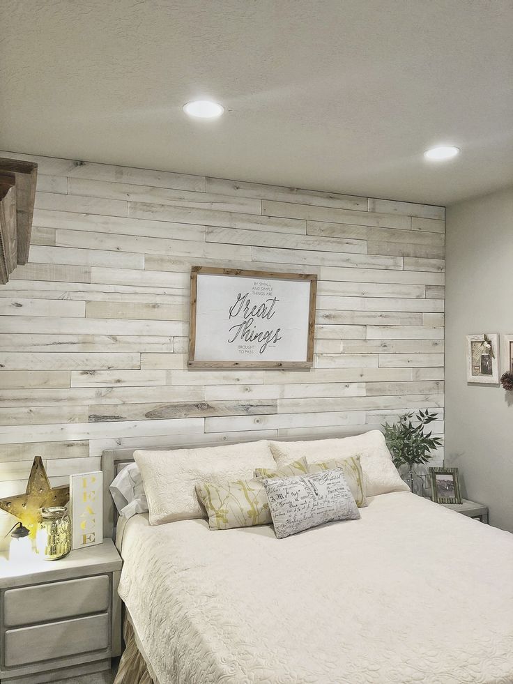 a white bed sitting in a bedroom next to a wall with a wooden sign above it