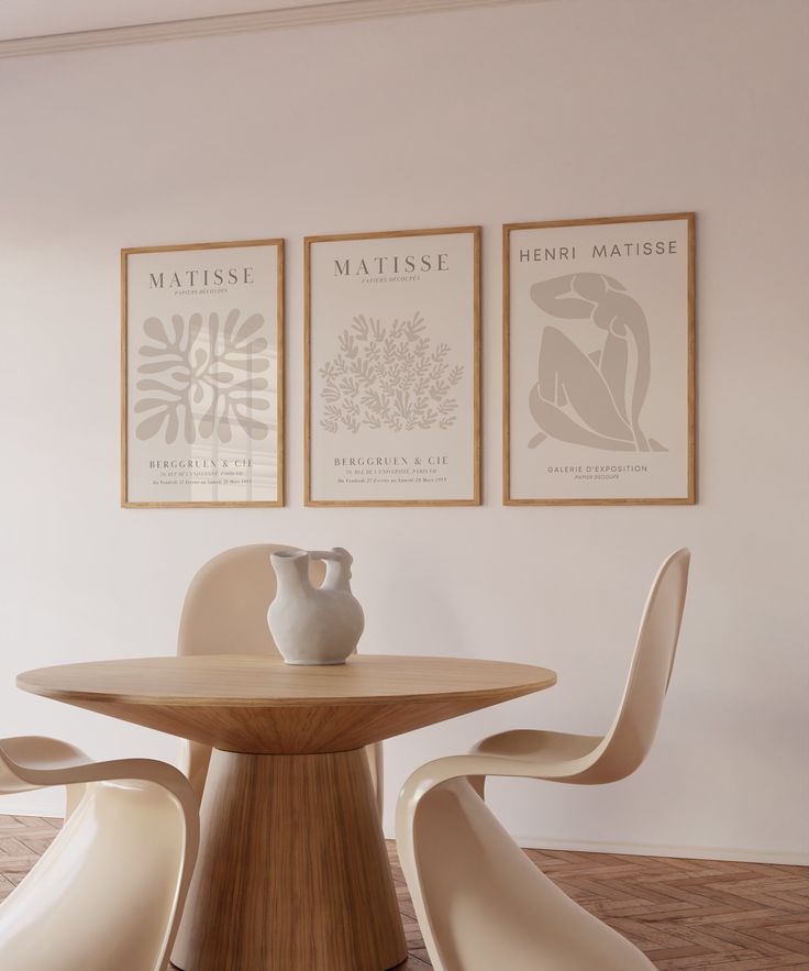 a table with two vases on it in front of three framed art pieces above it