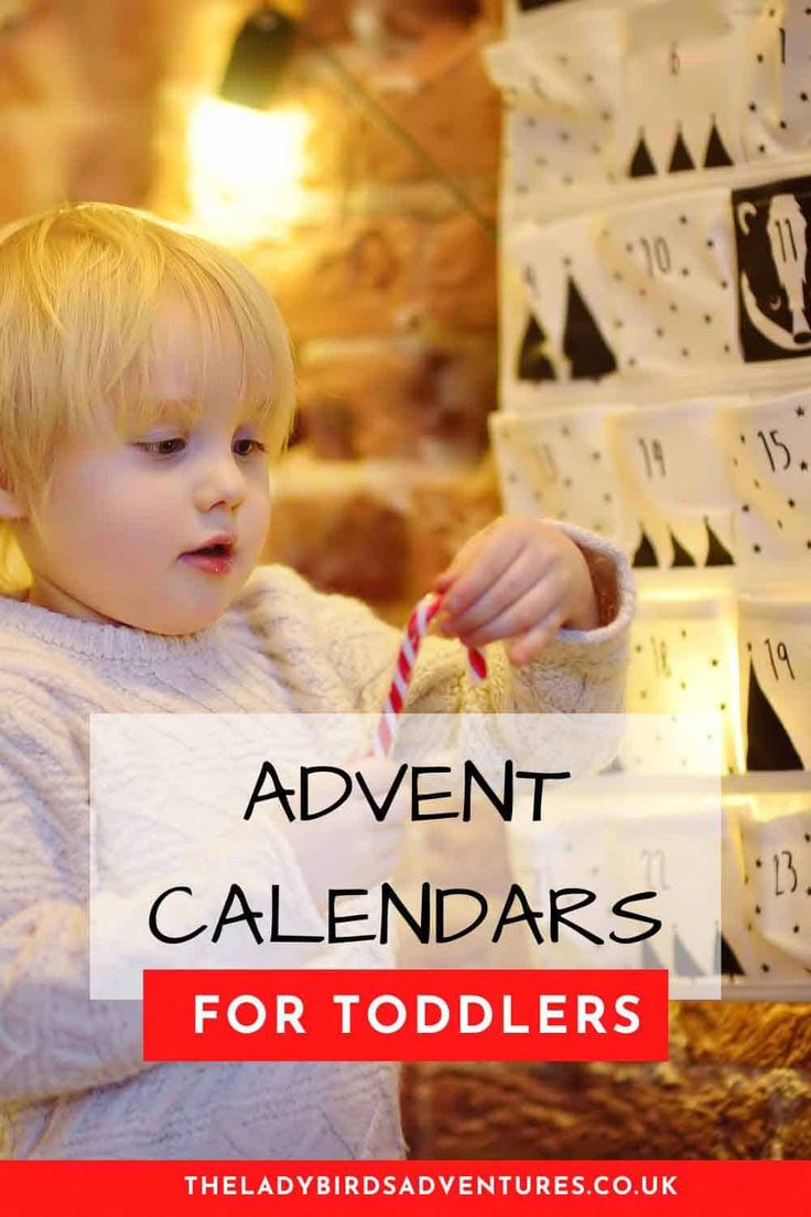 a little boy holding a candy cane in front of a wall with calendars on it