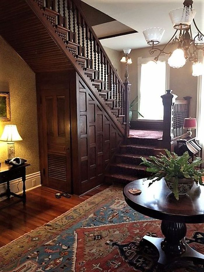 a living room filled with furniture next to a stair case and table on top of a rug