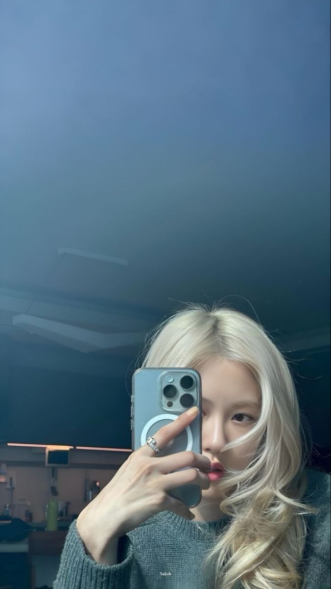 a woman taking a selfie with her cell phone in front of her face and long blonde hair