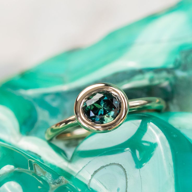 a close up of a ring on top of a green glass bowl with water in it