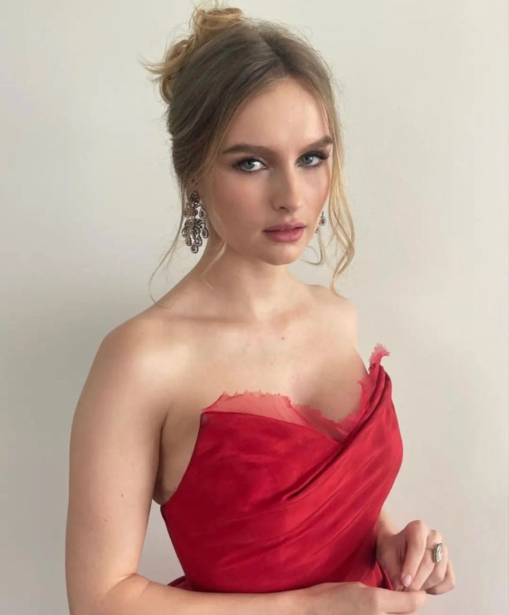 a woman in a red dress is posing for a photo with her hands on her hips