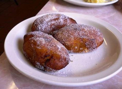 three donuts on a white plate with powdered sugar and eggs in the background