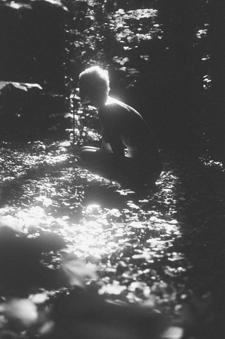 a young boy kneeling down in the woods