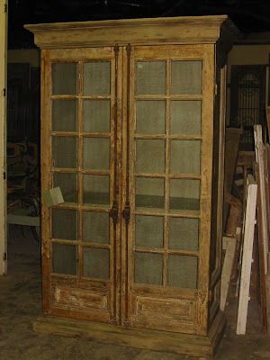 an old wooden armoire with glass doors in a room filled with wood and other items