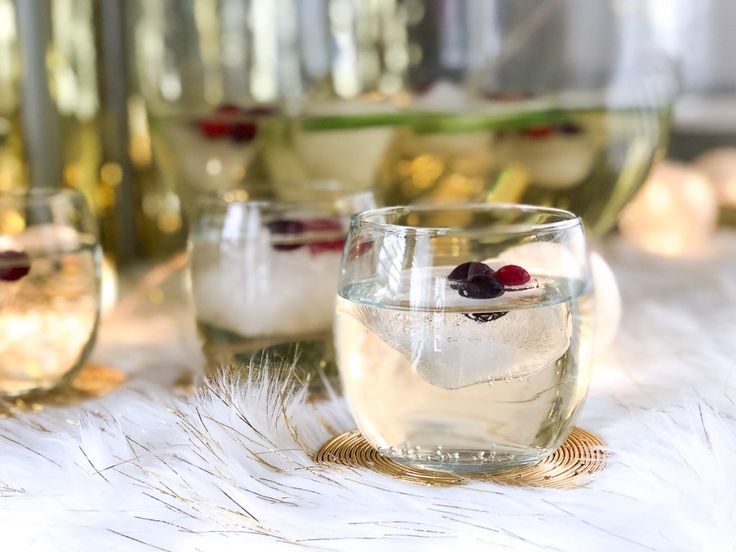 several glasses filled with different types of drinks on a white furnishing tablecloth