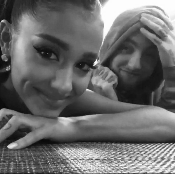 a woman laying on top of a wooden table next to a man in a black and white photo