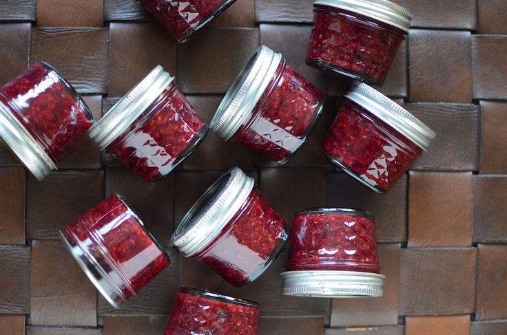 several jars filled with red liquid sitting on top of a woven table cloth next to each other