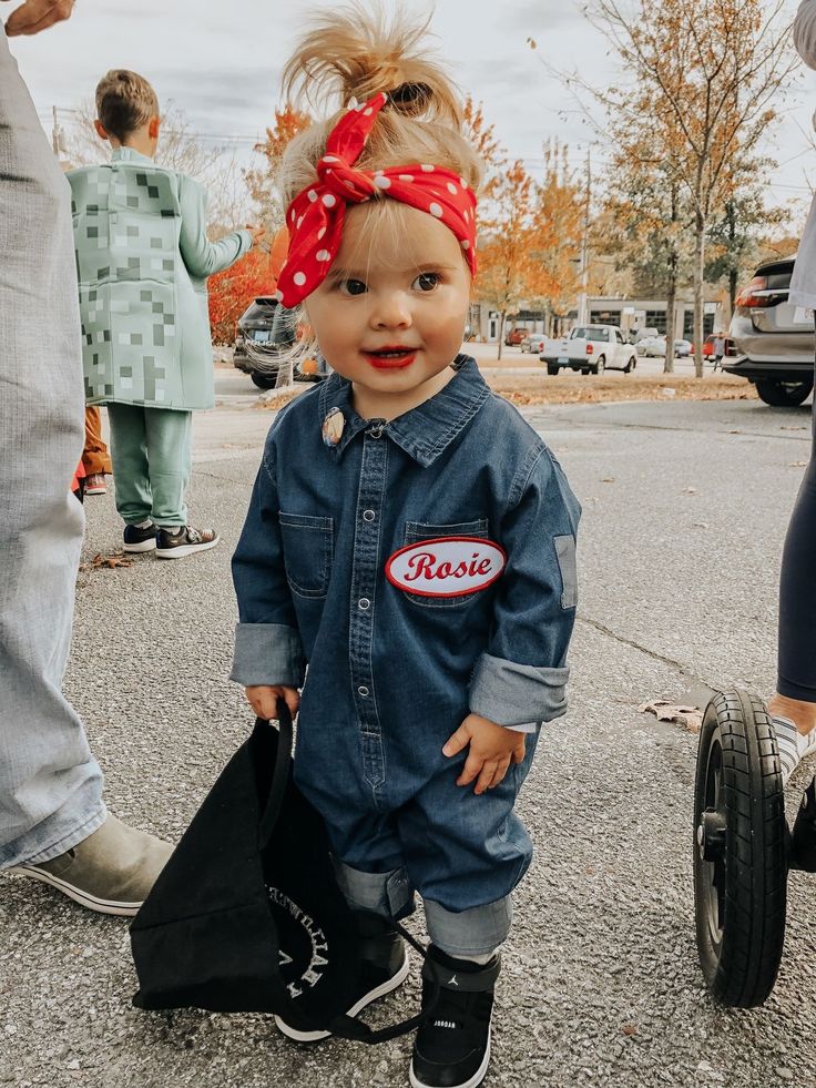 a toddler with a red bandana on her head is standing in the street