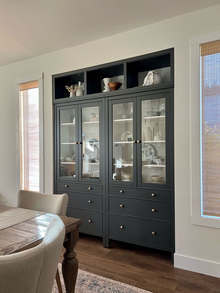 a dining room table and chairs in front of a large china cabinet with glass doors