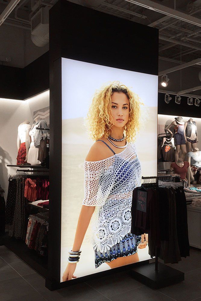 a display in a clothing store with a woman's image on the wall and clothes