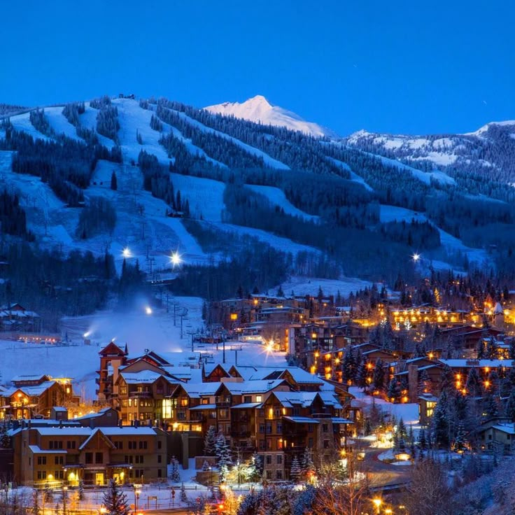 the town is lit up at night in the mountains