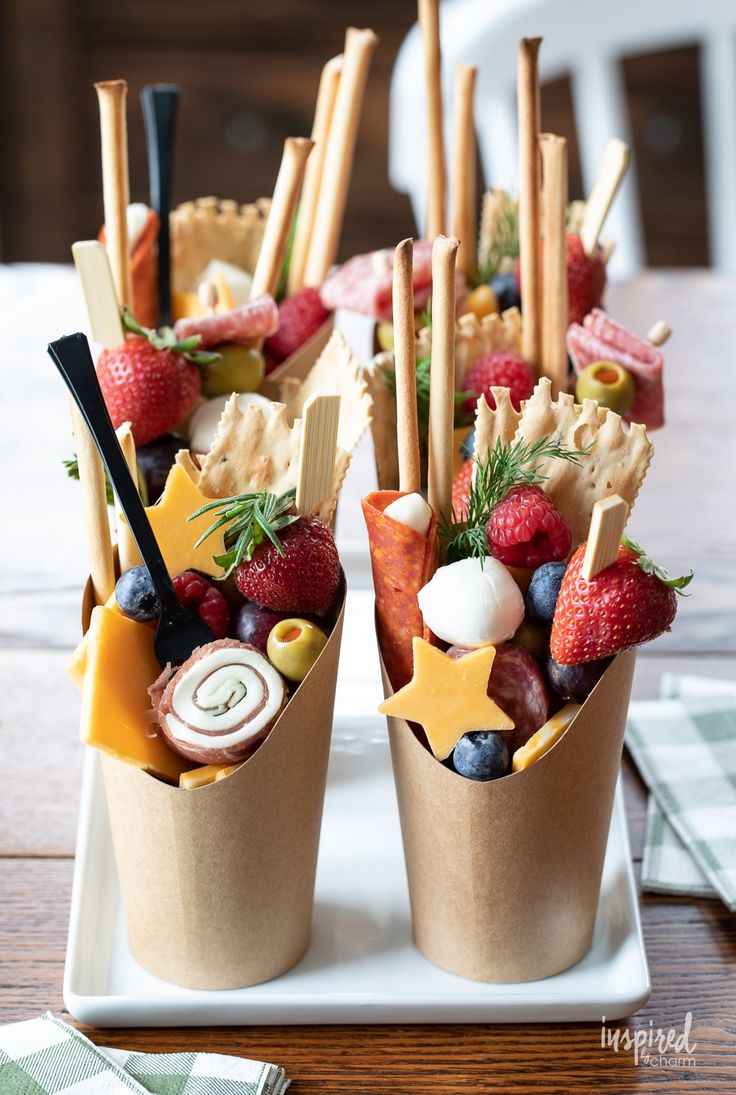 small cups filled with fruit and appetizers on top of a wooden table next to napkins